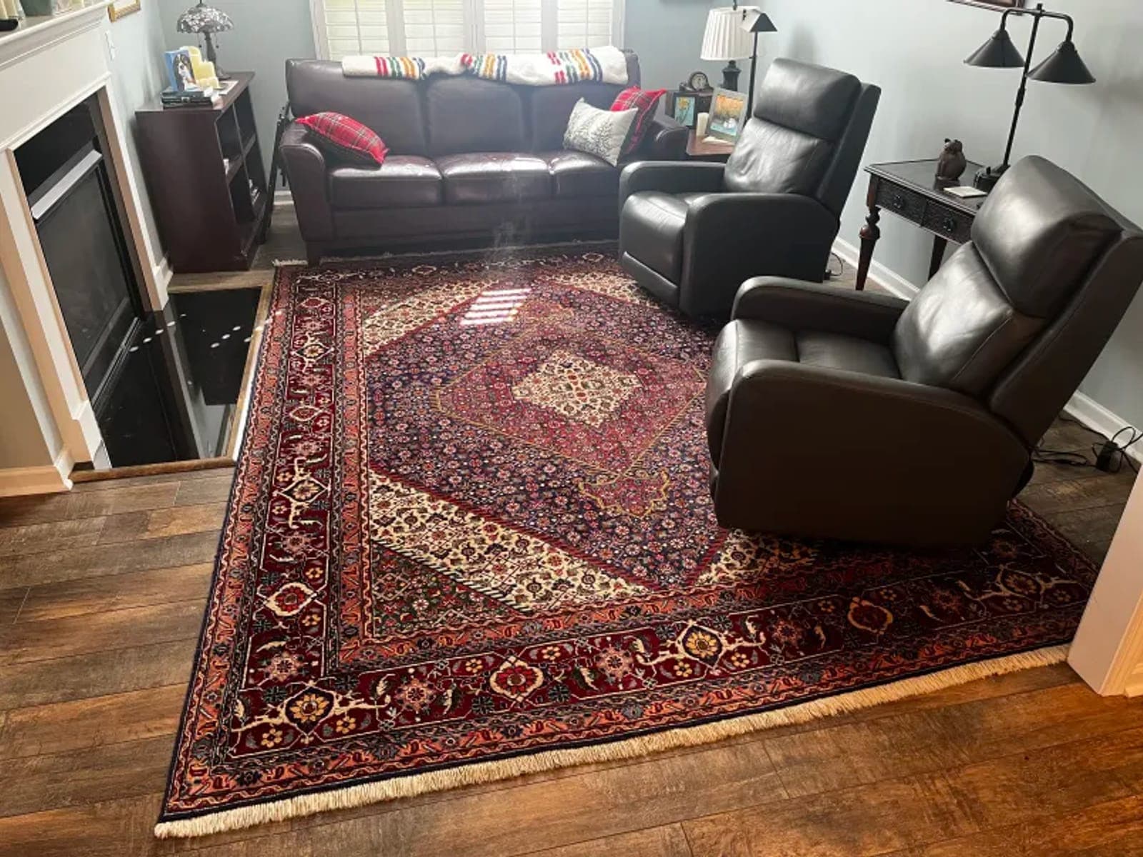 Large red-bordered area rug lying flat on a hardwood floor in a living room